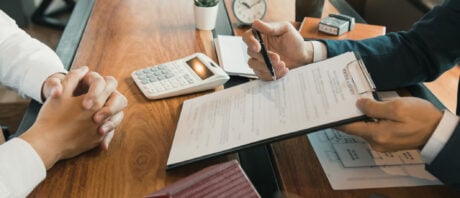 Two people are sitting at a desk with mortgage documents.