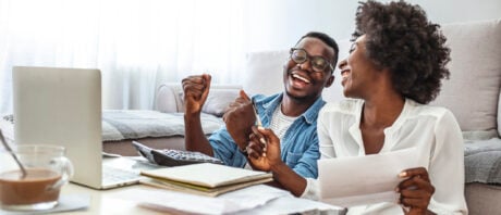 Happy couple with laptop celebrates opening a TFSA GIC.