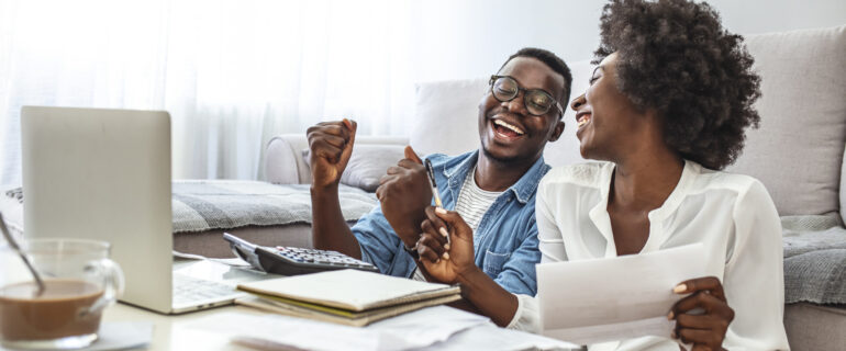 Happy couple with laptop celebrates opening a TFSA GIC.