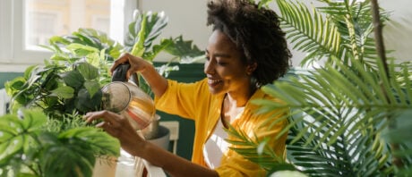 Black woman, taking care of plants in her new condo.