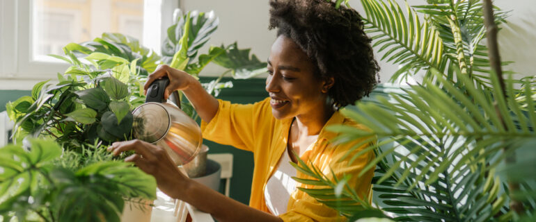 Black woman, taking care of plants in her new condo.