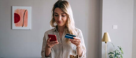 Smiling young woman holding a credit card.