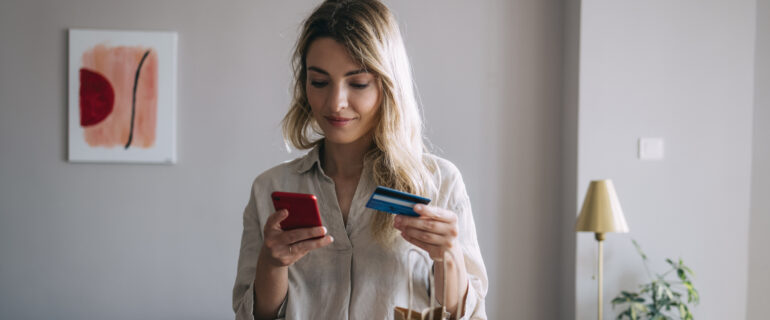 Smiling young woman holding a credit card.