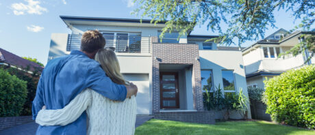 Couple stands in front of home purchased with subprime mortgage.