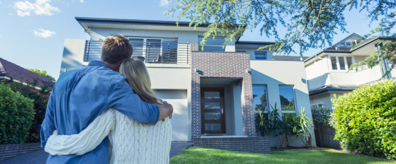 Couple stands in front of home purchased with subprime mortgage.