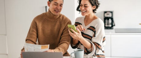 A couple in the kitchen setting up pre-authorized debit payments to pay bills in advance.