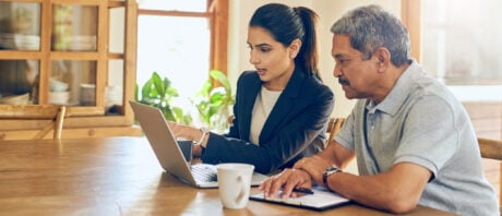 A man and woman look at a shared laptop, discussing property tax rates.