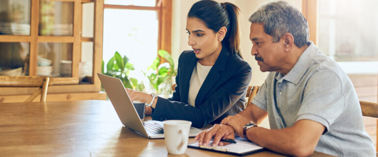 A man and woman look at a shared laptop, discussing property tax rates.