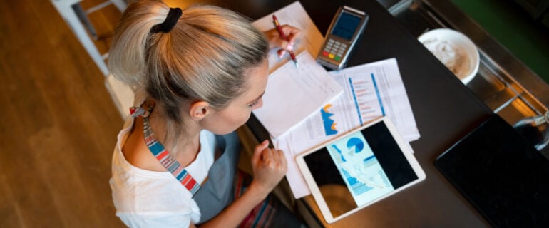 Woman in an apron uses money management tools on her laptop.