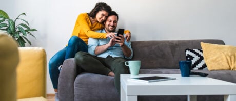 Cheerful couple on couch researching home insurance.