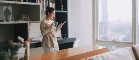 Asian women enjoys tea in her new living room after buying a condo.