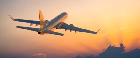 Passenger airplane flying above clouds during sunset