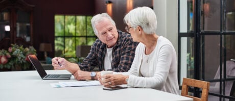 Senior couple uses a laptop while discussing the executor of their will.