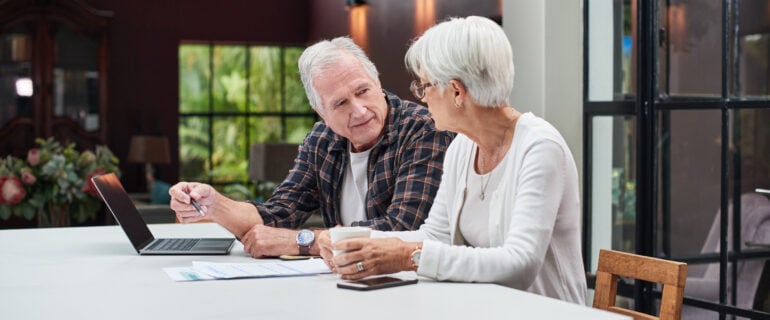 Senior couple uses a laptop while discussing the executor of their will.