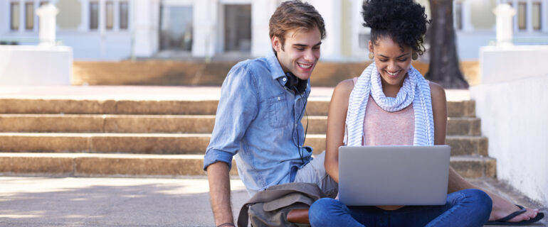 Two college-aged friends share a laptop while researching ETFs vs mutual funds vs index funds.