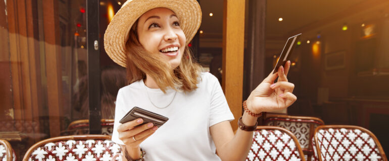 Woman in a hat pays for her cafe meal with a metal credit card.