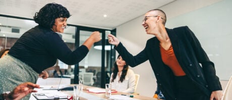 Business women fist bump each other after learning about their RRSP matching program.