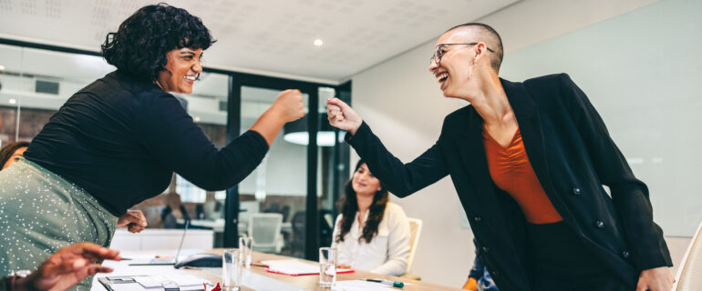 Business women fist bump each other after learning about their RRSP matching program.