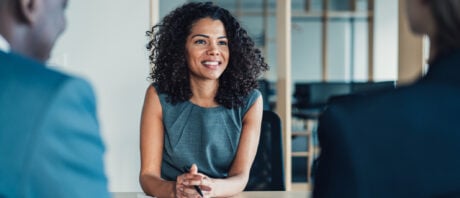 Woman negotiates her salary across a table with two executives.