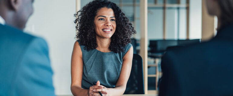 Woman negotiates her salary across a table with two executives.