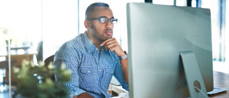 Young man at computer thinks about buying crypto with a credit card.