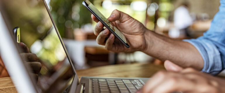 Image of a person’s arm on the laptop setting up direct deposit online using the routing number.