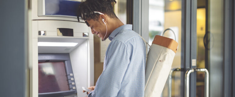 Young man is withdrawing money from an ATM