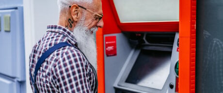 Senior man seen at an ATM taking advantage of free ATM withdrawals in Canada.