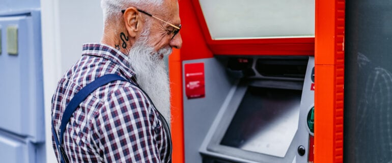 Senior man seen at an ATM taking advantage of free ATM withdrawals in Canada.