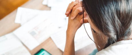 Young woman sitting on the sofa, checking her finances on the phone app., comparing the total cost for a personal loan vs. a line of credit.