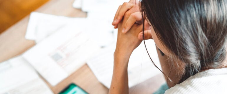 Young woman sitting on the sofa, checking her finances on the phone app., comparing the total cost for a personal loan vs. a line of credit.