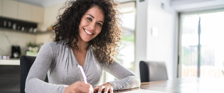 Portrait of a mid-adult woman filling her SIN number application form at home