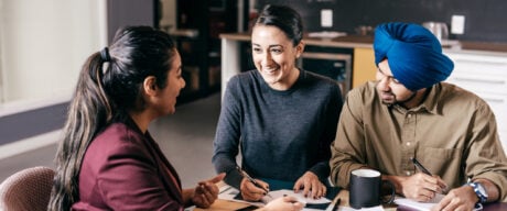 South Asian couple confirming the CIBC GIC rates with a bank financial advisor at the table.