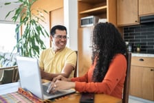 Mid-adult couple reviewing their RBC TFSA balance using laptop at home.