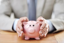 Cropped image of a businessman's hands covering a piggy bank.