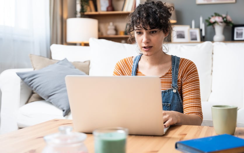 Headshot of a pleasant happy young woman logging into her CRA account on the laptop at home.