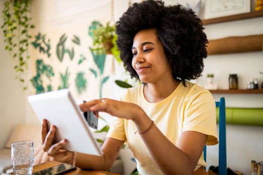 A smiling young woman checking her BMO Performance chequing account balance on her tablet.