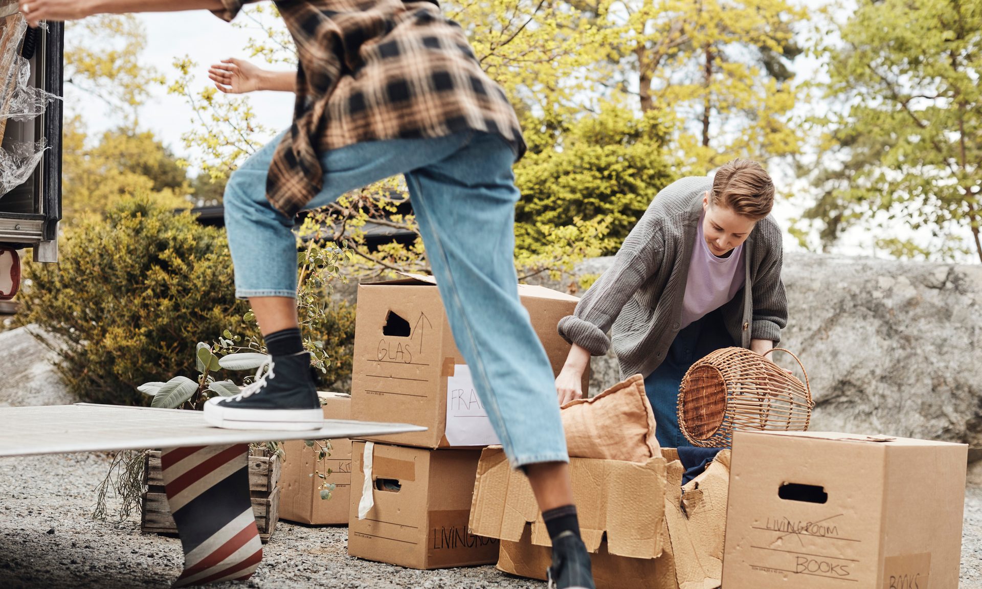 Couple helping each other while arranging cardboard boxes outside van