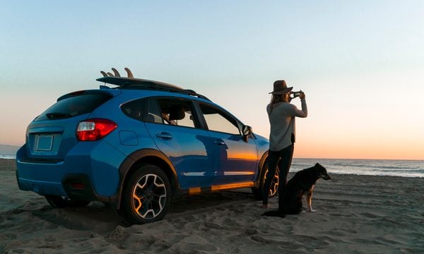 Woman on beach with car and dog