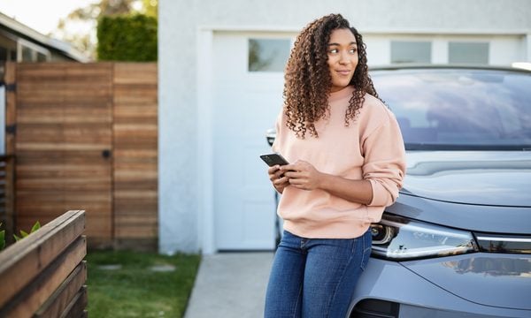 Woman sitting on car with phone