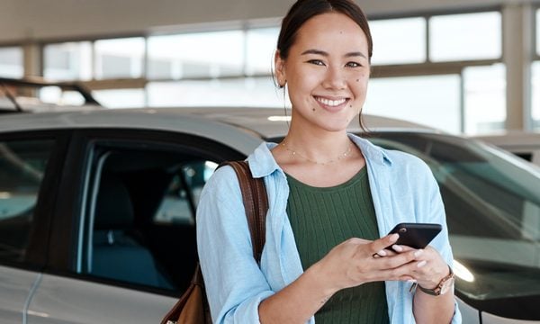 Happy young woman at car dealership