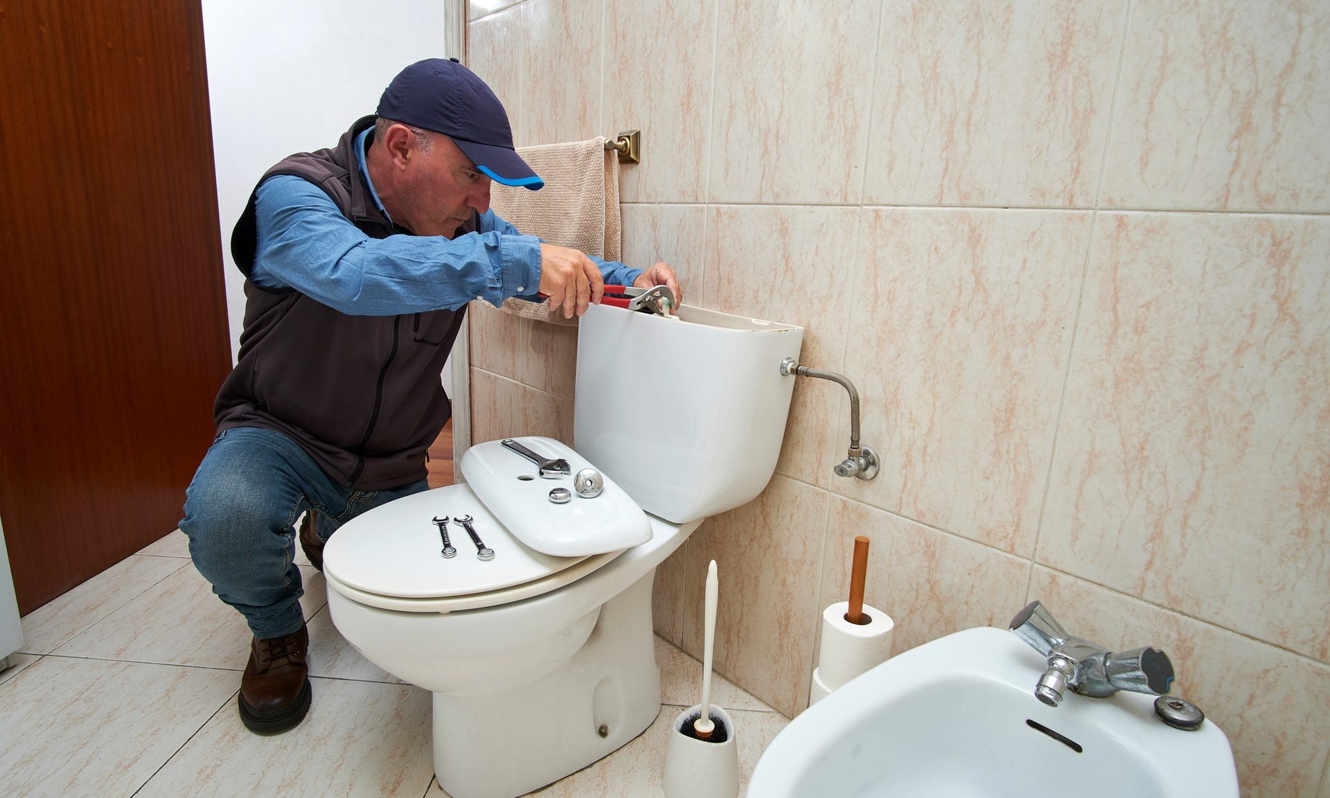 Plumber repairing a toilet.