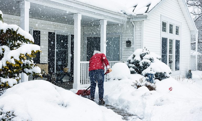 person shoveling snow outside their house