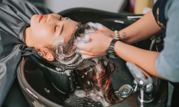 Directly above Asian chinese female lying down for hair wash at hair salon with eyes closed