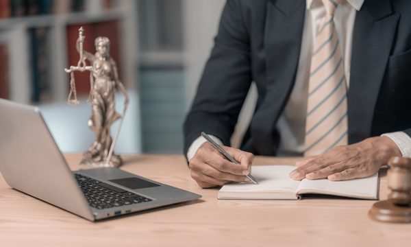 Lawyer writing in a notebook next to laptop