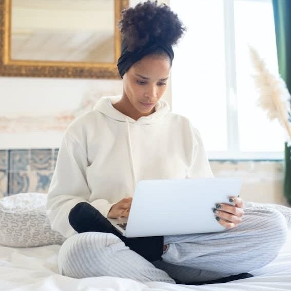 Young woman using laptop on bed