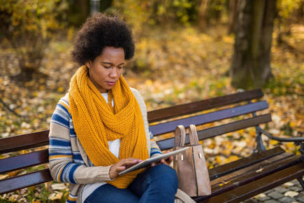 Woman reading Autumn budget rumours on a bench
