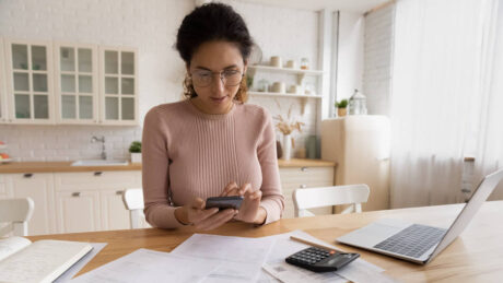 Woman at home using a calculator to prepare finances