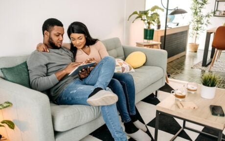Couple looking at remortgaging fees on sofa
